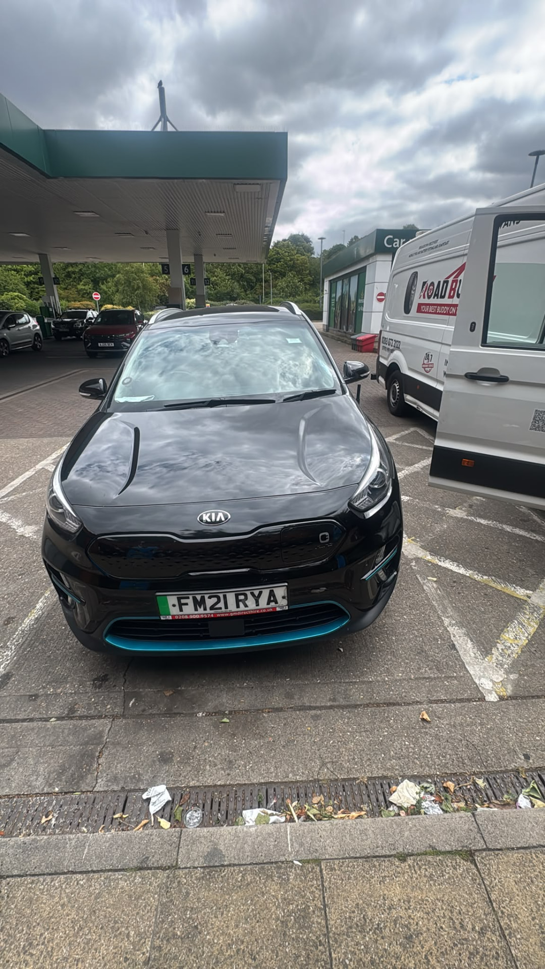 Black hybrid SUV on a service station forecourt with the Road Buddy van behind during a mobile tyre fitting job in Milton Keynes