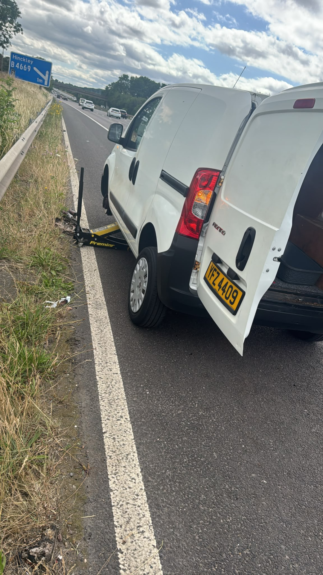 White van jacked up on the verge of a dual carriageway near Hinckley during an emergency tyre replacement